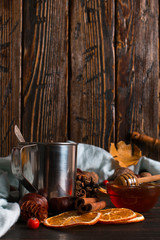 Iron mug with black coffee, honey, spices, on a background of a scarf, dry leaves on a wooden table. Autumn mood, a warming drink. Copy space.