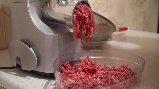 Preparation of minced beef with an electric meat grinder. Raw meat in a mincer