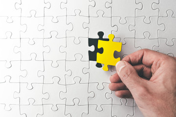 top view of hand holding last matching puzzle piece right before completion