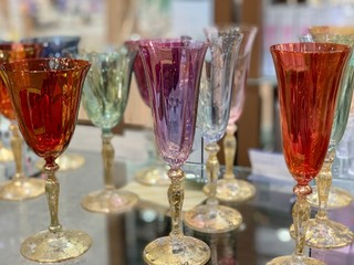 Colored wine glasses on a shelf in a store. Glassware for drinks made of transparent glass. Crystal glasses for the holiday.
