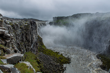 Panoramic view of the waterfall. Puffs of steam and spray of water fall on a high rocky shore
