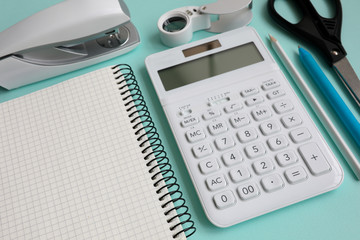 Stationery with white calculator lie on blue table epty modern