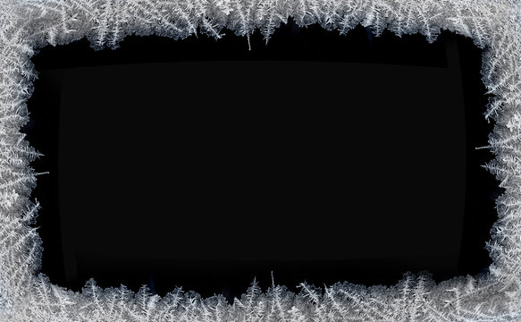 Decorative ice crystals on a window in form of a frame on black matte backgroundP
