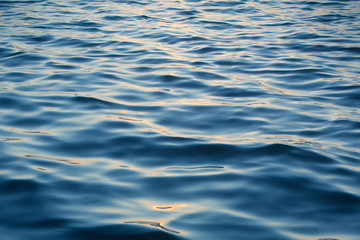 Infinite background of water waves in lake. Blue to black colors. Natural texture.