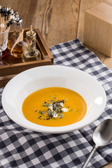 Pumpkin cream soup with seeds on fabric napkin on wooden table
