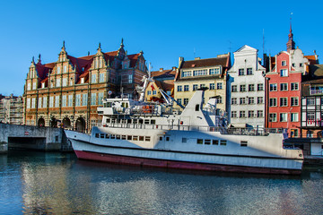 Tourist ship and historic houses next to Motlawa river in port of Gdansk, Baltic Sea, Poland.