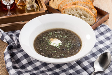Thick forest mushroom soup with potatoes on fabric napkin on wooden table