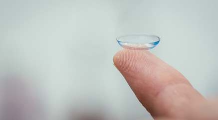 Contact lens lying on a male finger, macro close up. Customer, patient or eye doctor. Copy space.