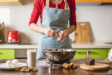Cook housewife making cookies at home on a colorful kitchen. Woman rubbing on grater cinnamon to...