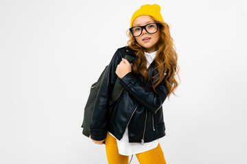 Teenager caucasian girl with yellow hat holds a big backpack in her hands isolated on white background