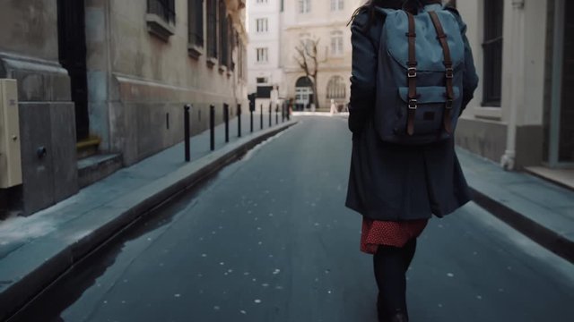 Close-up camera follows beautiful elegant woman with backpack walking along autumn Paris streets posing slow motion.