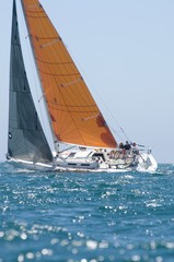 Yacht With Orange Sail Competes In Team Sailing Event