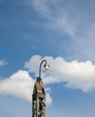 old lantern on a metal pole against the background of sky and clouds. lonely electric lamp with an...