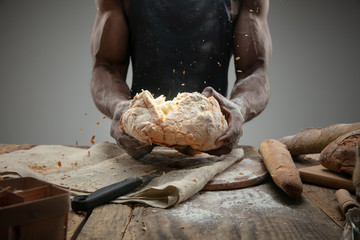 Close up of african-american man cooks fresh cereal, bread, bran on wooden table. Tasty eating, nutrition, craft product. Gluten-free food, healthy lifestyle, organic and safe manufacture. Handmade.