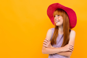 Pretty young girl with red hir and big red hat looks aside isolated on white background