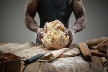 Close up of african-american man cooks fresh cereal, bread, bran on wooden table. Tasty eating, nutrition, craft product. Gluten-free food, healthy lifestyle, organic and safe manufacture. Handmade.