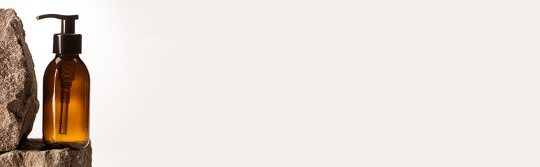 dispenser cosmetic bottle on stones on white background with back light, panoramic shot