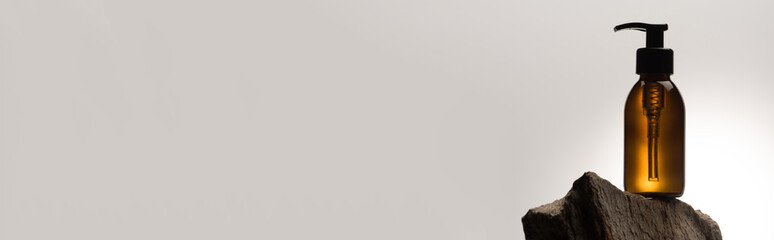 dispenser cosmetic bottle on stone on white background with back light, panoramic shot