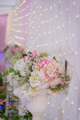 Plastic flowers placed near the wall decorated with lights.