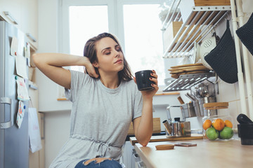 young woman drinking morning coffee in her kitchen