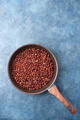 Roasted peanuts in a pan on a blue textured background.