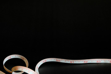 Selective focus blurred shot of measuring tape isolated on black background with copy space for text. Health, diet and fitness concept. take care of body, fit and firm with strong and healthy life.