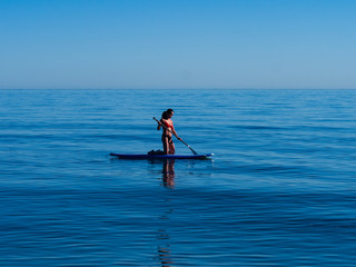 Fototapeta na wymiar Asian woman kneeling on standup paddle board Sea of Cortez.
