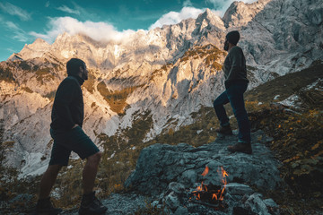 Obraz premium Two hikers in front of an impressive alpine mountain range at sunset.
