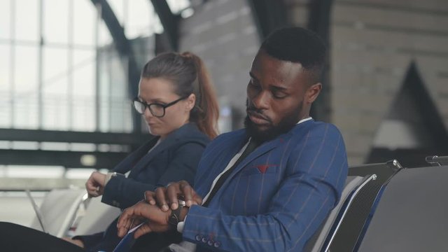 Young tired businessman and businesswoman in airport business lounge waiting for flight