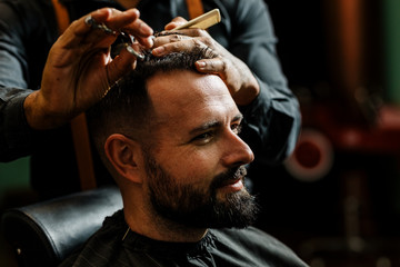 un barbero afroamericano brasileño esta cortando con tijeras y peine el pelo de la cabeza (cuero...