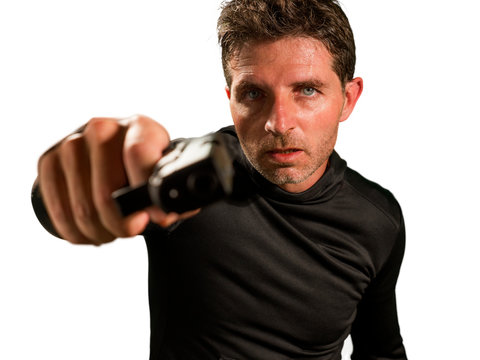 action portrait of angry and attractive hitman or special agent man holding gun pointing the handgun to camera isolated on white background in secret service