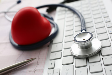 Stethoscope head lying on white keyboard