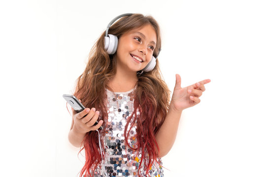 Little pretty caucasian girl listen to music with big earphones and dancing, picture isolated on white background