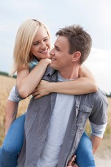 Romantic young man piggybacking woman on field