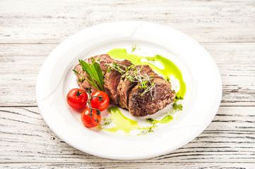 Chateaubriand in a restaurant close-up. Beef tenderloin steak with tomatoes on a white plate and copy space.