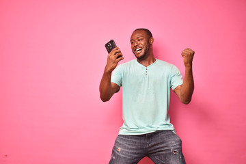 handsome excited young black man feeling excited while viewing content on his smartphone,...
