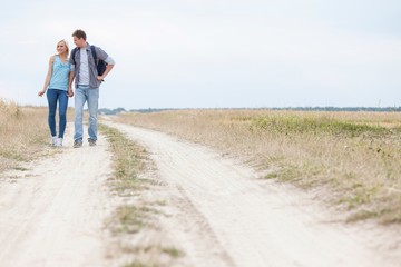 Full length of young hiking couple standing on trail at field