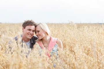 Happy loving young couple sitting amidst field