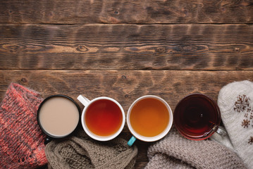 Various hot drink such as herbal tea, green tea, black tea,milk tea and warm clothes on wooden table background.