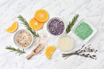 Scented sea salt with lavender, oranges, rosemary for spa and bath, flat lay on marble background.
