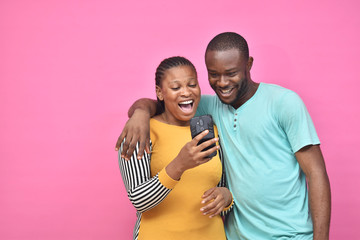 two young african friends, boy and girl, looking excited while viewing something on their smartphone together