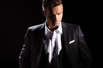 Confident businessman looking down isolated on black