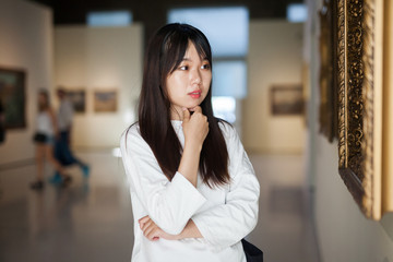Obraz premium Chinese young woman near picture collection in the museum