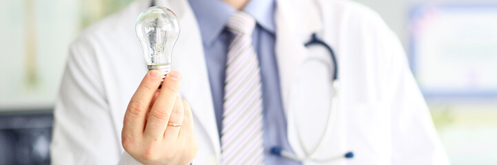 Male doctor hand holding lightbulb as bright idea invention symbol