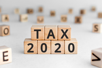 Tax 2020 - phrase from wooden blocks with letters, Tax time 2020 concept, random letters around, white  background