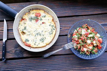 Homemade omelet in a pan and cucumber and tomato salat