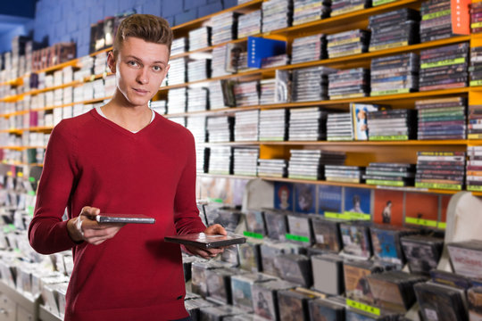Young man absorbedly choosing CD and DVD in store