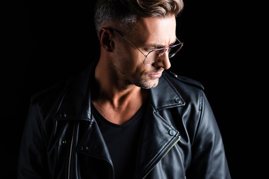 Stylish man in leather jacket looking away isolated on black