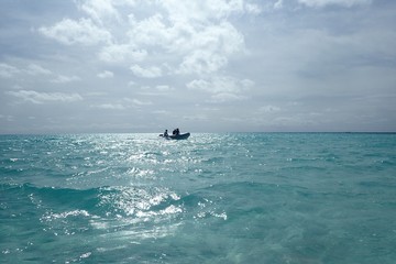  a small motorboat furrows the silver sea of ​​the maldives