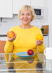 Woman with plate of fruits at kitchen